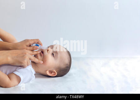 Mère a mis l'administration de gouttes de solution saline dans le nez du bébé. Petit garçon obtenir des gouttes. 6 mois bébé garçon obtient nez gouttes. Pédiatre de gouttes de solution saline en mettant infan Banque D'Images