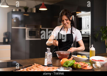Smiling woman cooking in kitchen tendant une sauce Banque D'Images