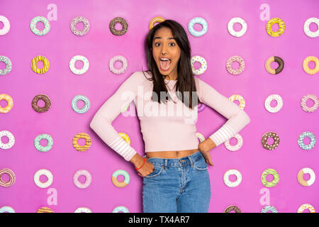 Jeune femme criant à un parc à thème couvert avec donuts au mur Banque D'Images