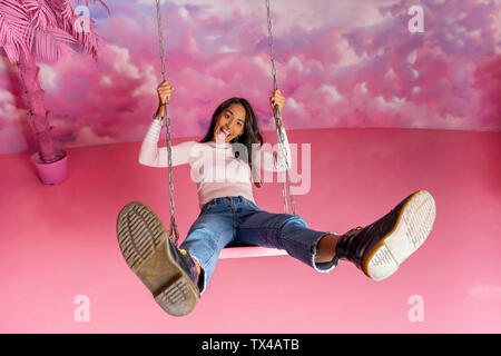 Portrait de jeune femme sur une balançoire à un parc à thème couvert Banque D'Images