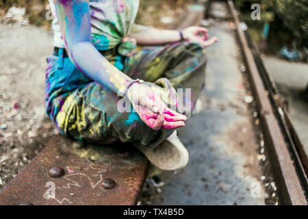 Fille aux couleurs de Holi sur ses vêtements assis sur pont, meditationg, Allemagne Banque D'Images