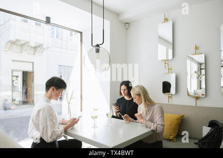 Trois jeunes femme l'utilisation de téléphones cellulaires dans le Banque D'Images