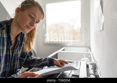 Jeune femme étudie les instructions de montage dans la cuisine Banque D'Images