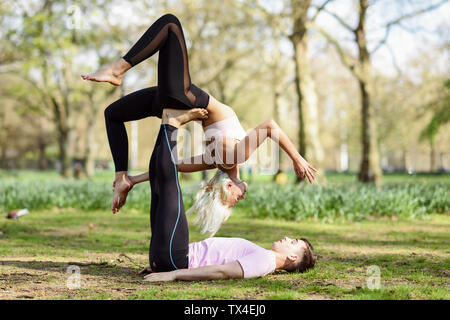 Jeune couple faisant du yoga l'acrobatie dans un parc urbain Banque D'Images