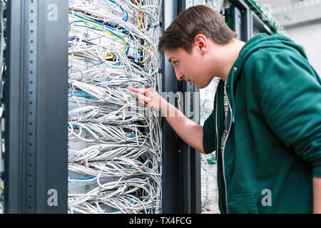 Adolescent travaillant avec les câbles dans la salle serveur Banque D'Images