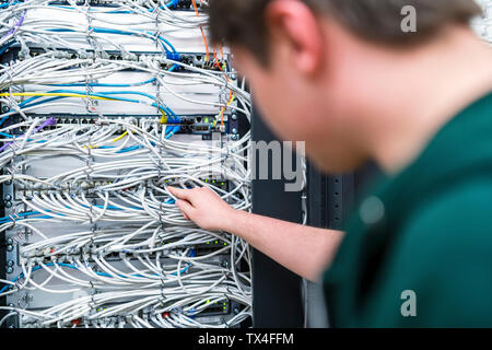 Close-up of adolescent travaillant avec les câbles dans la salle serveur Banque D'Images