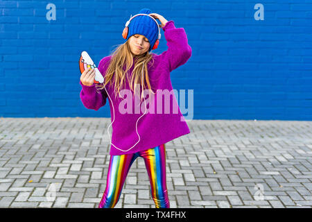 Portrait of Girl dancing en plein air tout en écoutant de la musique avec des écouteurs et smartphone Banque D'Images