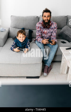 Portrait de père et fils à jouer à jeu ensemble sur le canapé Banque D'Images