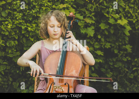 Une fille à jouer du violoncelle dans jardin Banque D'Images