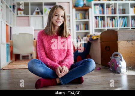 Certain fille assise en tailleur sur le plancher de sa chambre Banque D'Images