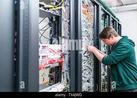 Adolescent travaillant avec les câbles dans la salle serveur Banque D'Images