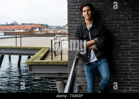 Danemark, copenhague, portrait of young man leaning contre un mur au bord de l'eau Banque D'Images