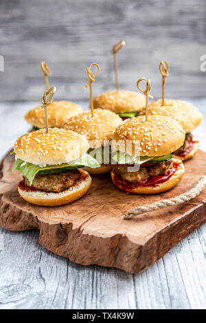 Mini-Burger avec la viande hachée, salade, tomate et concombre sur plateau en bois Banque D'Images