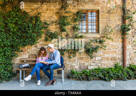 Jeune couple sur un séjour en ville, assis sur un banc, prenant une pause Banque D'Images