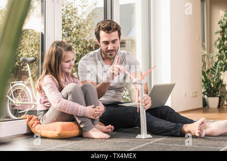 Jeune homme et petite fille jouant avec le modèle d'une éolienne Banque D'Images