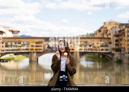 Italie, Florence, jeune femme touristiques manger un cornet de crème glacée au Ponte Vecchio Banque D'Images