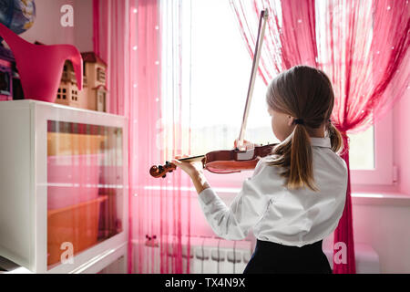 Fille à jouer du violon à la fenêtre à la maison Banque D'Images