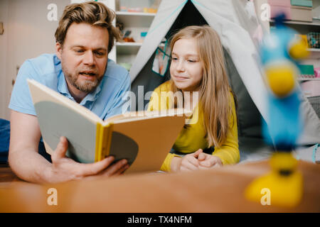 Père et fille à la lecture du livre dans la chambre des enfants Banque D'Images