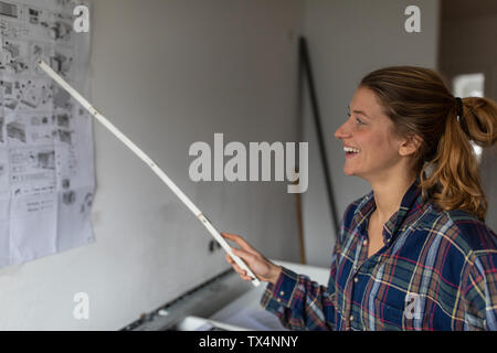 Happy young woman studying instructions de montage sur le mur Banque D'Images