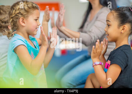 Heureux les enfants et enseignante préscolaire clapping hands en maternelle Banque D'Images