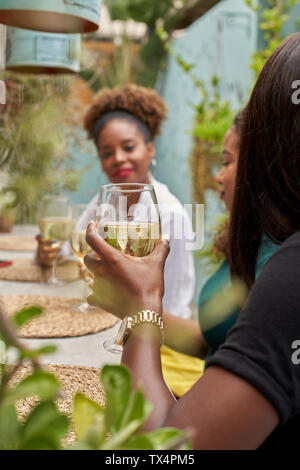 Femme assise dans un restaurant avec ses amis drinking white wine Banque D'Images