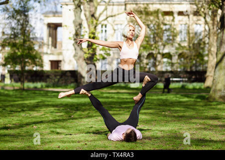 Jeune couple faisant du yoga l'acrobatie dans un parc urbain Banque D'Images