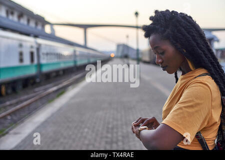 Jeune femme sur la plate-forme à la gare de vérifier sa montre Banque D'Images