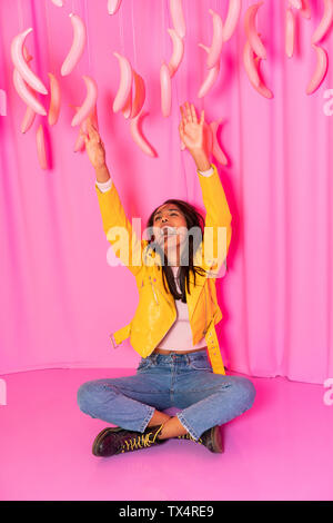 Jeune femme criant à un parc à thème couvert avec ballants bananes rose Banque D'Images