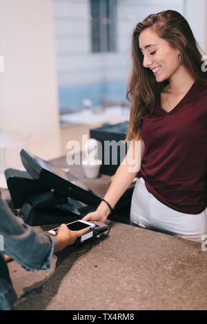 Portrait de femme de payer sans espèces avec le smartphone à un magasin de détail Banque D'Images