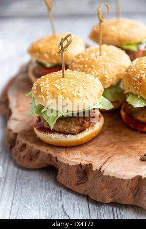 Mini-Burger avec la viande hachée, salade, tomate et concombre sur plateau en bois Banque D'Images