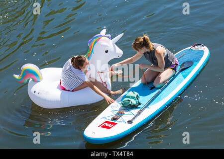 Femme paddleboarder paddle boarder et gonflables gonflables unicorn s'amusant sur Dorset Canot Journée à Rivière Stour, Iford, Dorset UK en Juin Banque D'Images