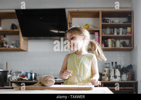 Happy little girl rouler la pâte dans la cuisine Banque D'Images