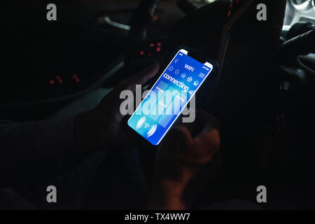 Close-up of young man connexion du smartphone avec wifi dans la voiture à la nuit Banque D'Images