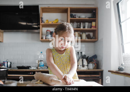 Portrait of smiling little girl le pétrissage pâte dans la cuisine Banque D'Images