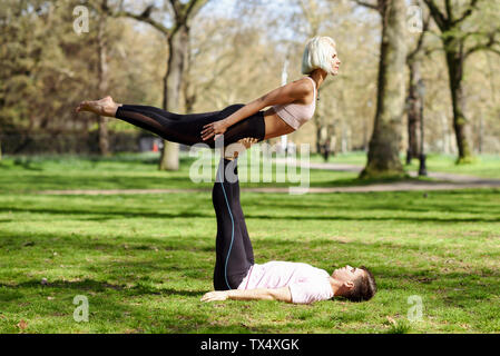 Jeune couple faisant du yoga l'acrobatie dans un parc urbain Banque D'Images