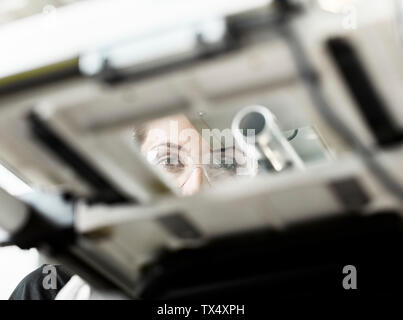 Femme au travail sur machine, looking at camera Banque D'Images