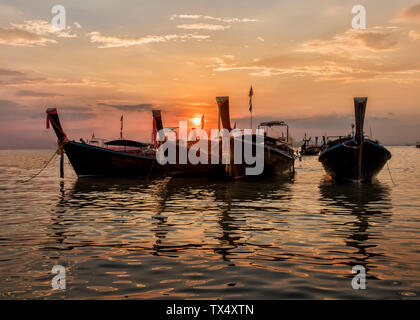 La Thaïlande, Krabi, Railay beach, long-tail bateaux flottant sur l'eau au coucher du soleil Banque D'Images