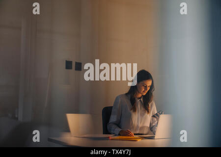 Young businesswoman travaillant tard at desk in office Banque D'Images