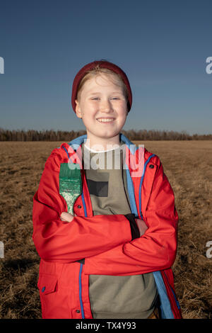 Portrait of smiling boy holding pinceau dans paysage de steppe Banque D'Images