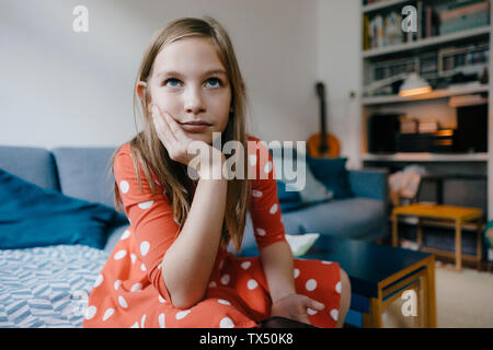 Portrait of serious girl sitting on sofa at home Banque D'Images