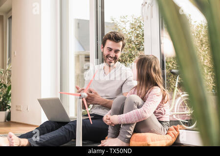 Jeune homme et petite fille jouant avec le modèle d'une éolienne Banque D'Images