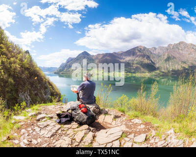 L'Italie, la Lombardie, le printemps au lac d'Idro, randonneur assis avec la carte au point d'observation Banque D'Images