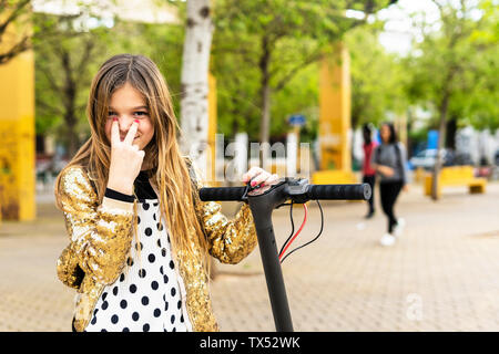 Portrait of smiling girl with scooter portant veste sequin d'or Banque D'Images