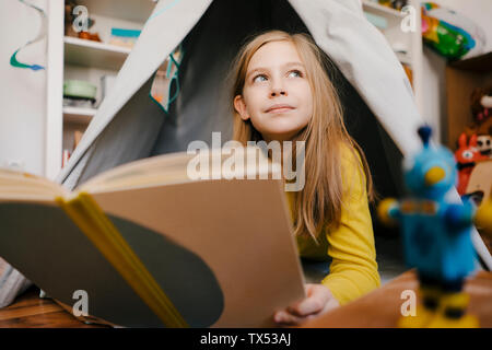 Girl at home reading book in chambre enfants Banque D'Images