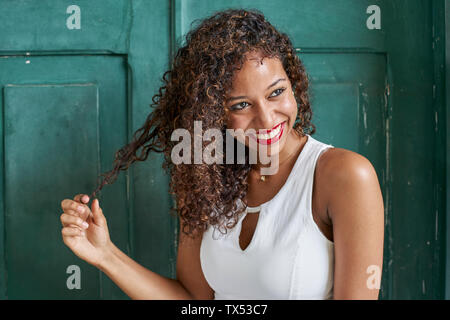 Portrait de jeune femme avec des cheveux bouclés en face de porte en bois vert Banque D'Images