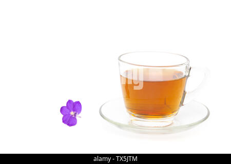 Du thé dans une tasse en verre avec fleur pourpre isolé en fond blanc. Banque D'Images