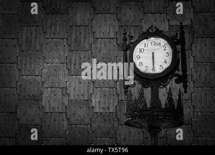 Vintage horloge analogique contre mur en béton noir Banque D'Images