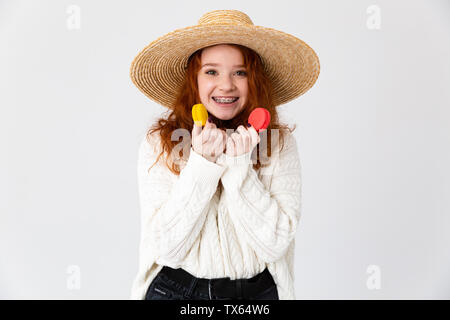 Close up portrait of a young woman wearing hat été isolés sur fond blanc, macarons holding Banque D'Images