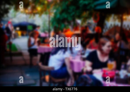 Abstract blurred restaurant en plein air plein d'invités dans la soirée. Arrière-plan flou artistique cafe. Banque D'Images