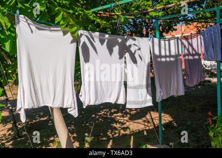 Blanchisserie en train de sécher dehors en plein air en été sous le soleil, en partie sous l'ombre des arbres Banque D'Images
